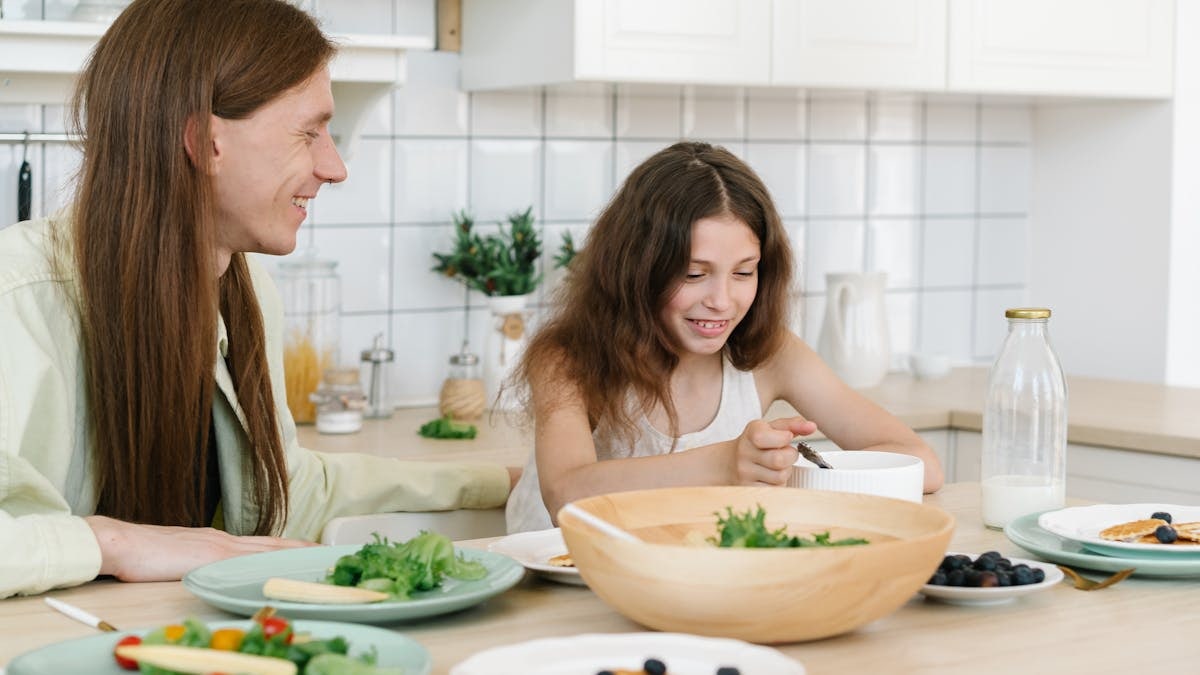 Father and daughter sharing a joyful breakfast at home in the kitchen.